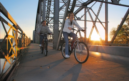 Couple Biking Across Bridge in Downtown Grand Forks All Four Seasons