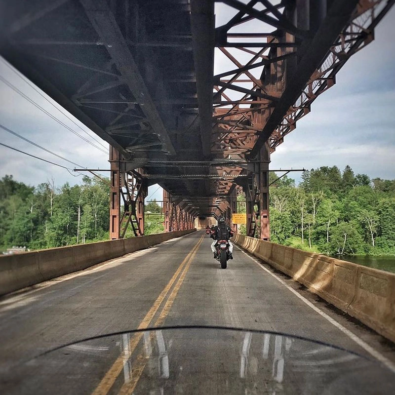 Brad-riding-his-motorcycle-on-a-bridge Brad on a bridge in Itasca state park