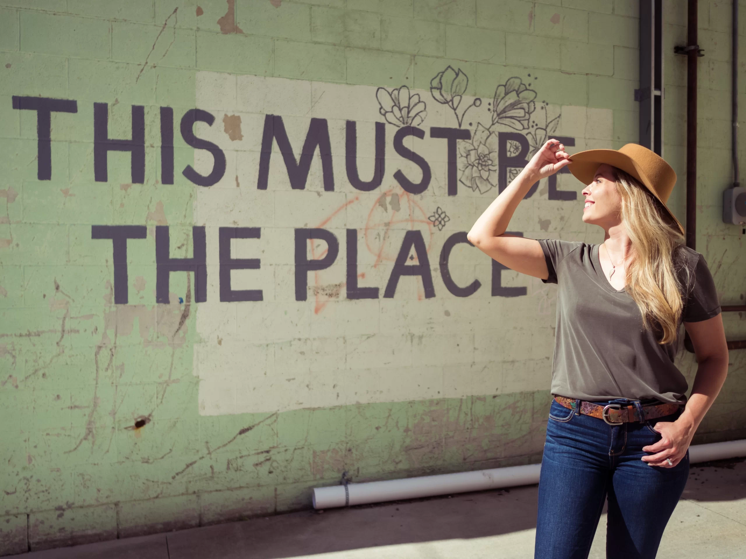 this-must-be-the-place Cassandra in front of a sign that reads 'this must be the place' in downtown Grand Forks.