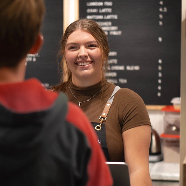 ember-coffeehouse-grand-forks-lauren Woman smiling at a customer at the Ember Coffeehouse in Grand Forks.
