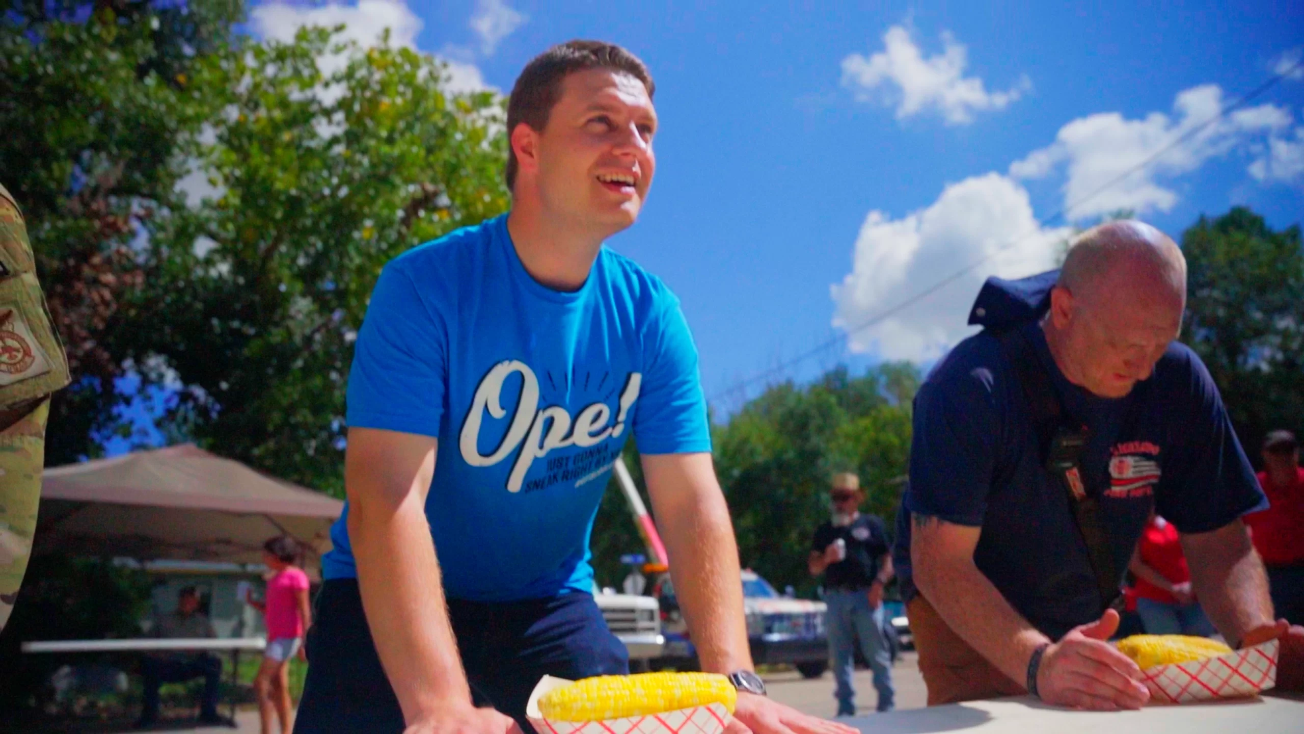 Colin-Corn-Contest-Grand-Forks-County Grand Forks is Cooler article picture. Colin wears blue shirt that reads "Ope!" and participates in Emerado Corn Feed.