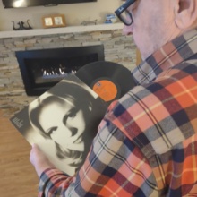 Over the shoulder picture of author Terry holding a vinyl record.