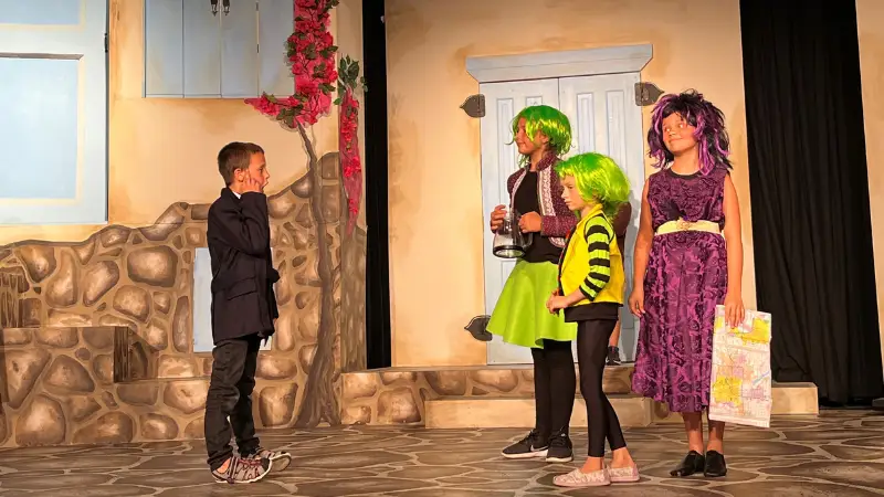 Grand-Forks-Theater Grand Forks Community theater scene where 4 kids stand on stage in vibrantly colored costumes