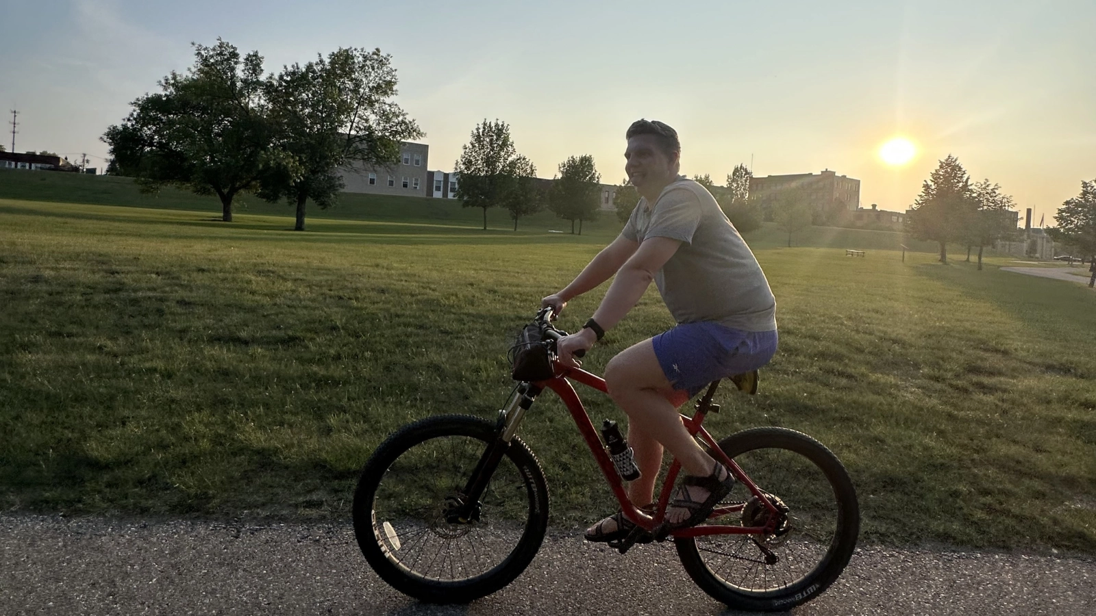paul-on-bike WCT author Paul makes a silly face while riding his bike down the Greenway. A sunset over a school in the back.