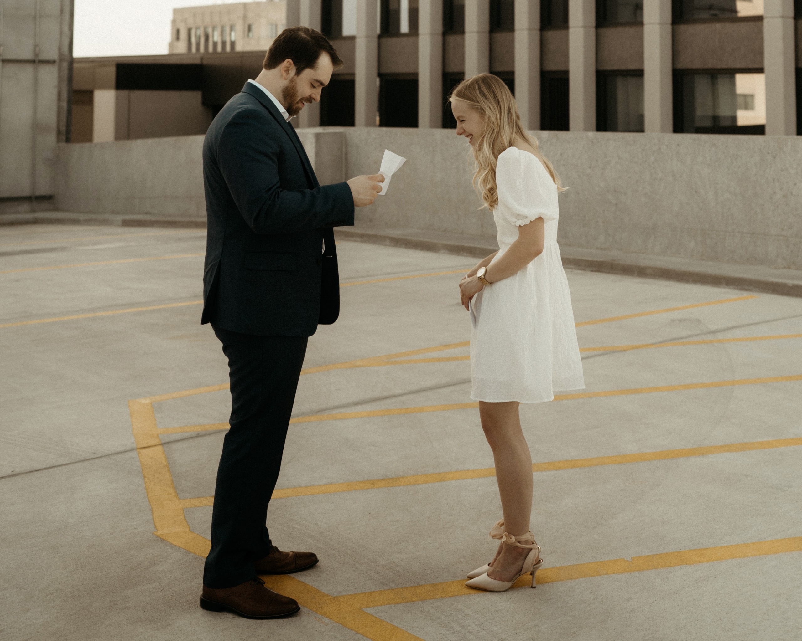 A couple smiles as they read their vows to each other on top of a parking garage in Grand Forks
