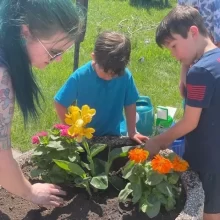 volunteer-planting Kids planting flowers for volunteering in Grand Forks.