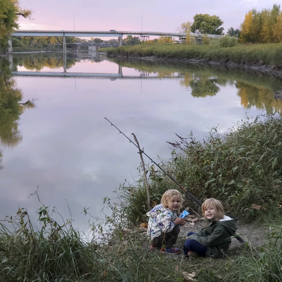 avery-and-jude-on-the-river-bank-in-grand-forks Jude and Avery Anderson fishing on the banks of the Red River at sunset.