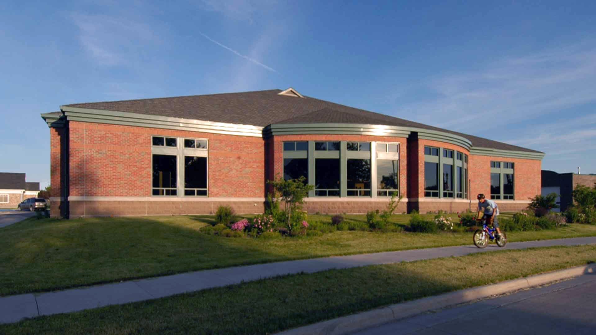 Grand Forks Libraries - Campbell Library A red brick building with a large dome bay window sits among a well-trimmed grass lawn.