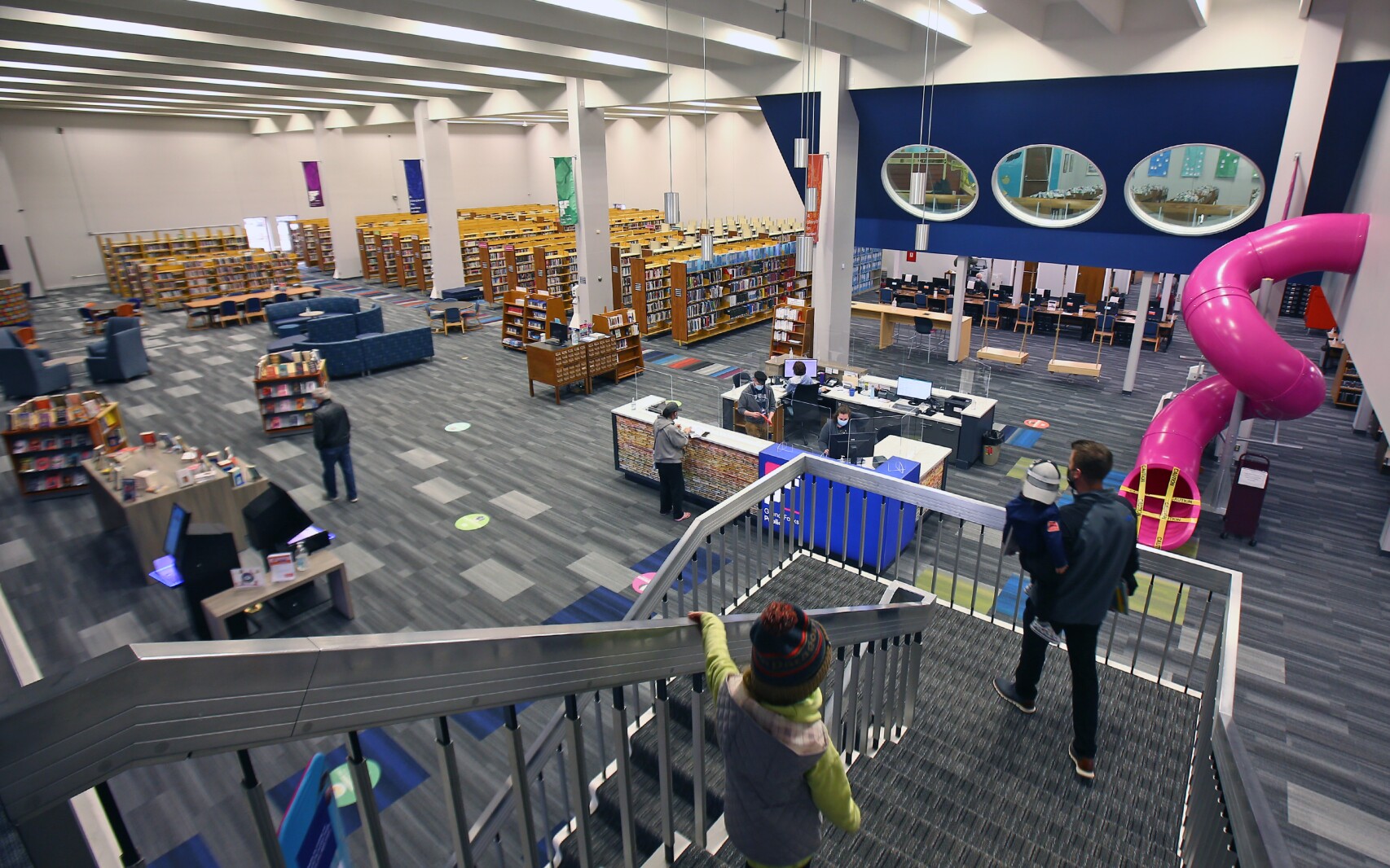 Grand Forks Libraries - GF Public The Interior of the Grand Forks Public Library showcases books, a grand staircase, and an aerial perspective of the second-story childrens's section, complete with a hot pink slide!