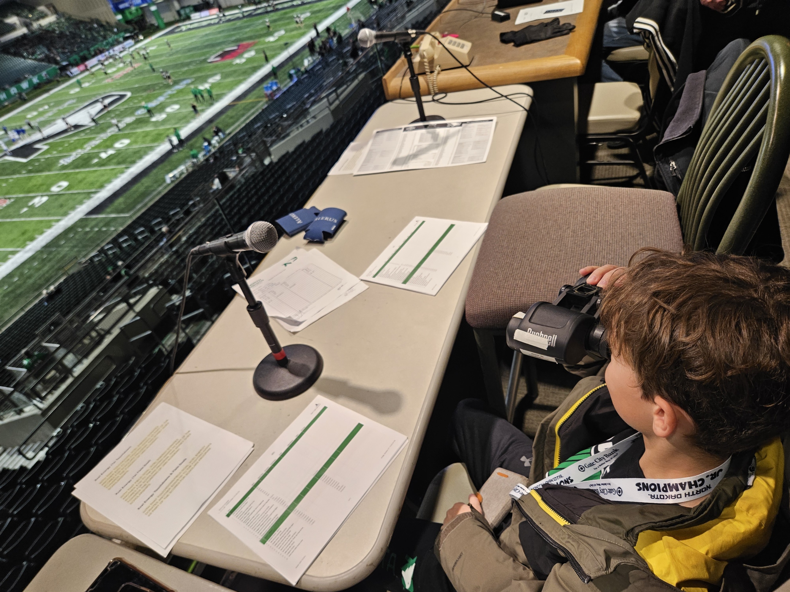 UND Athletics - Grand Forks is Cooler A young boy sits behind the mic at the announcement stand at a UND hockey game
