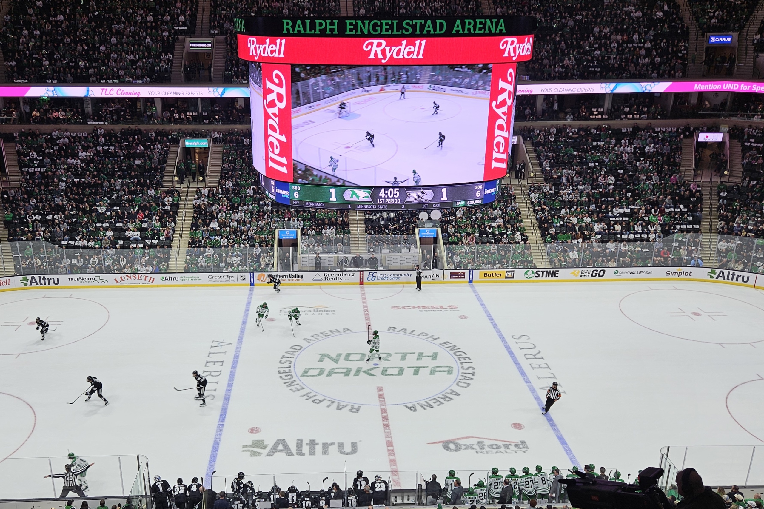 UND Athletics - Fighting Hawks - Ralph Englestad Arena An aerial view of a UND hockey game in action, the massive scoreboard above displaying a score of 1 to 1. The seats of the Ralph Engelstad Arena are almost completely full.