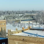 An image taken from atop a parking ramp building in downtown grand forks. Overlooks the bridge leading into downtown with the hoarfrost from winter encasing the scenery.