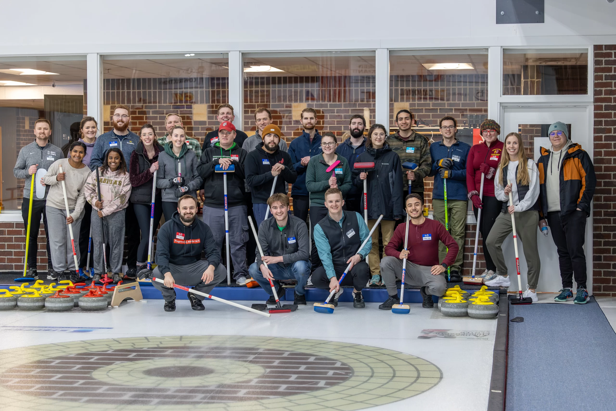 2024 Curling & Chili Cook-Off Grand Forks winter activities. A curling group stands together with curling equipment at the Grand Forks Curling Club.
