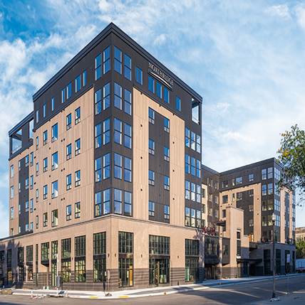 Franklin on 4th Exterior Exterior image of Franklin on 4th Apartments. Big tall building with tan and black colored accents. Loads of tall windows on the corners of the building and smaller windows for the individual apartments.