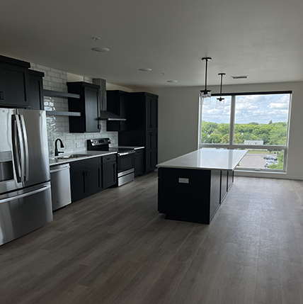 SpiritattheBeacon - isabelle k - photo Interior of Spirit at the Beacon kitchen. Black cabinets and silver appliances with a floor to ceiling window. White tile backsplash.