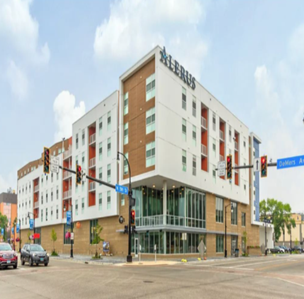 Pure North Apartments Exterior of Pure North Apartments. Entrance to the first floor grocery store on face the camera. Lots of glass windows on the corner. Building has white and brown siding with red-orange accents.