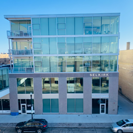 selkirk on 4th Glass walls surround the building on the top three floors. Glass balconies on the left hand side. Building is shorter with only five stories.