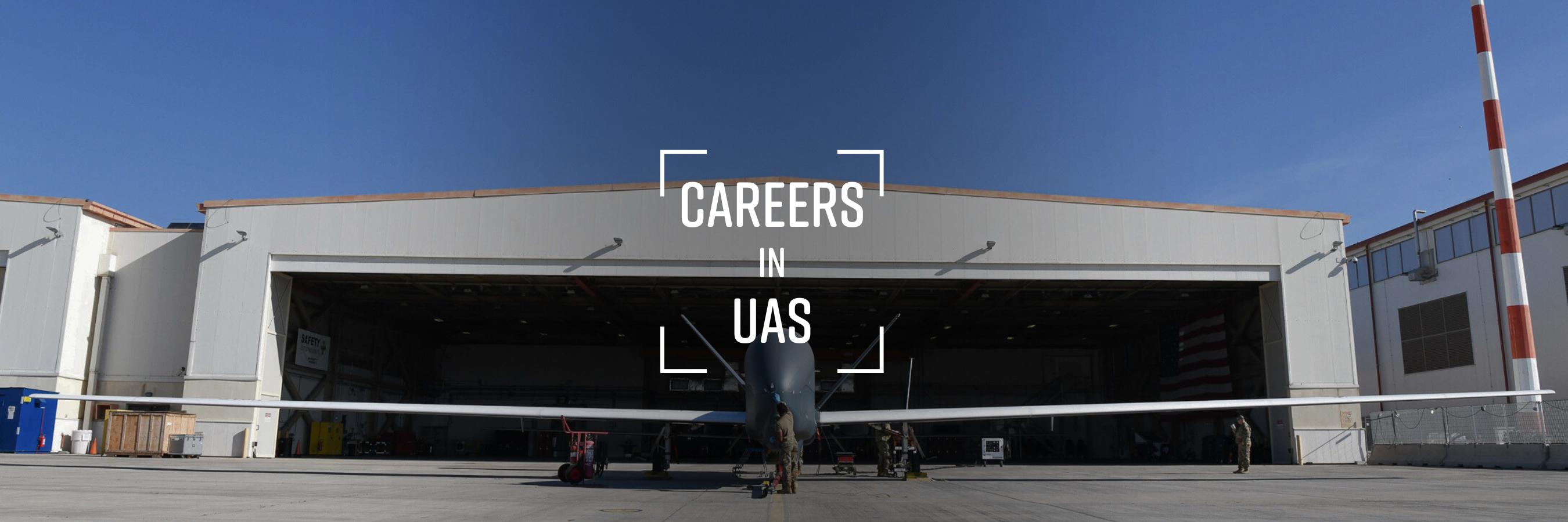 Grand Forks Careers in UAS Grand Forks Careers in UAS unmanned and autonomous systems. This is a image of a Global Hawk at a hangar at Grand Forks Air Force Base. A man in a military uniform stands in front of it.