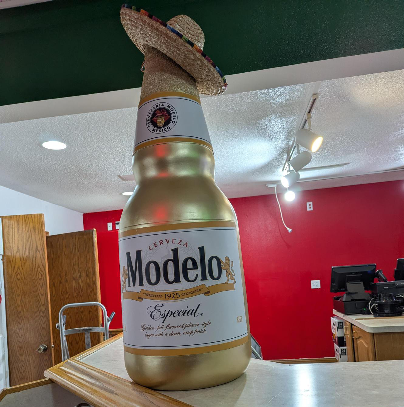A photo inside Las Delicias de la Abuela of a giant statue of a Modelo bottle wearing a sombrero.