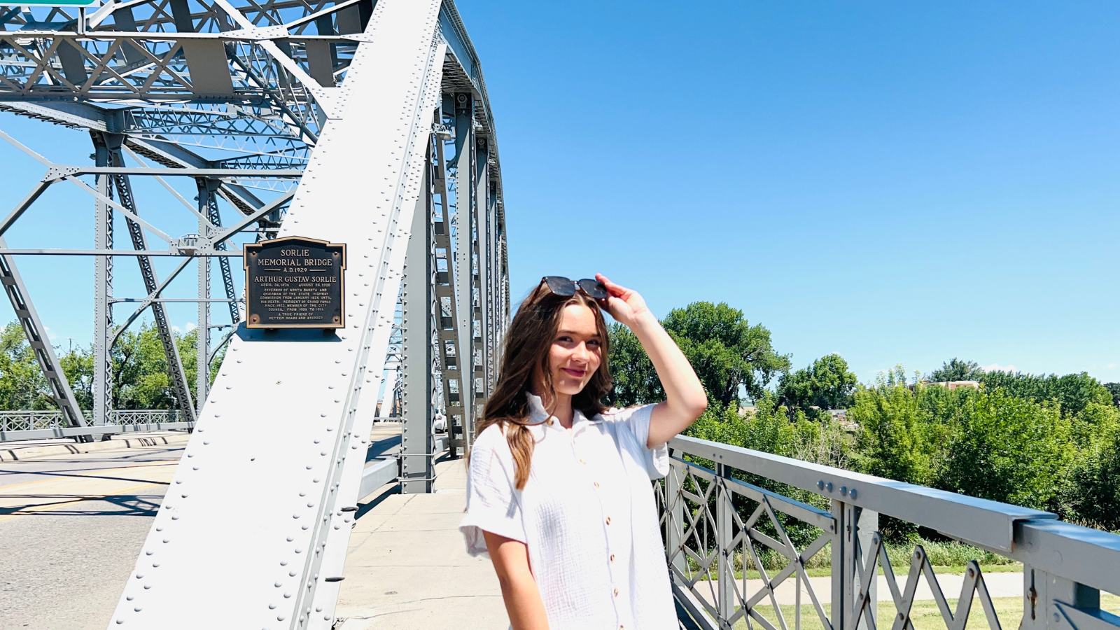 Natalie Sorlie bridge photo Author Natalie poses from the waist up at the start of the ND side of the Sorlie bridge, smiling in the sunshine.