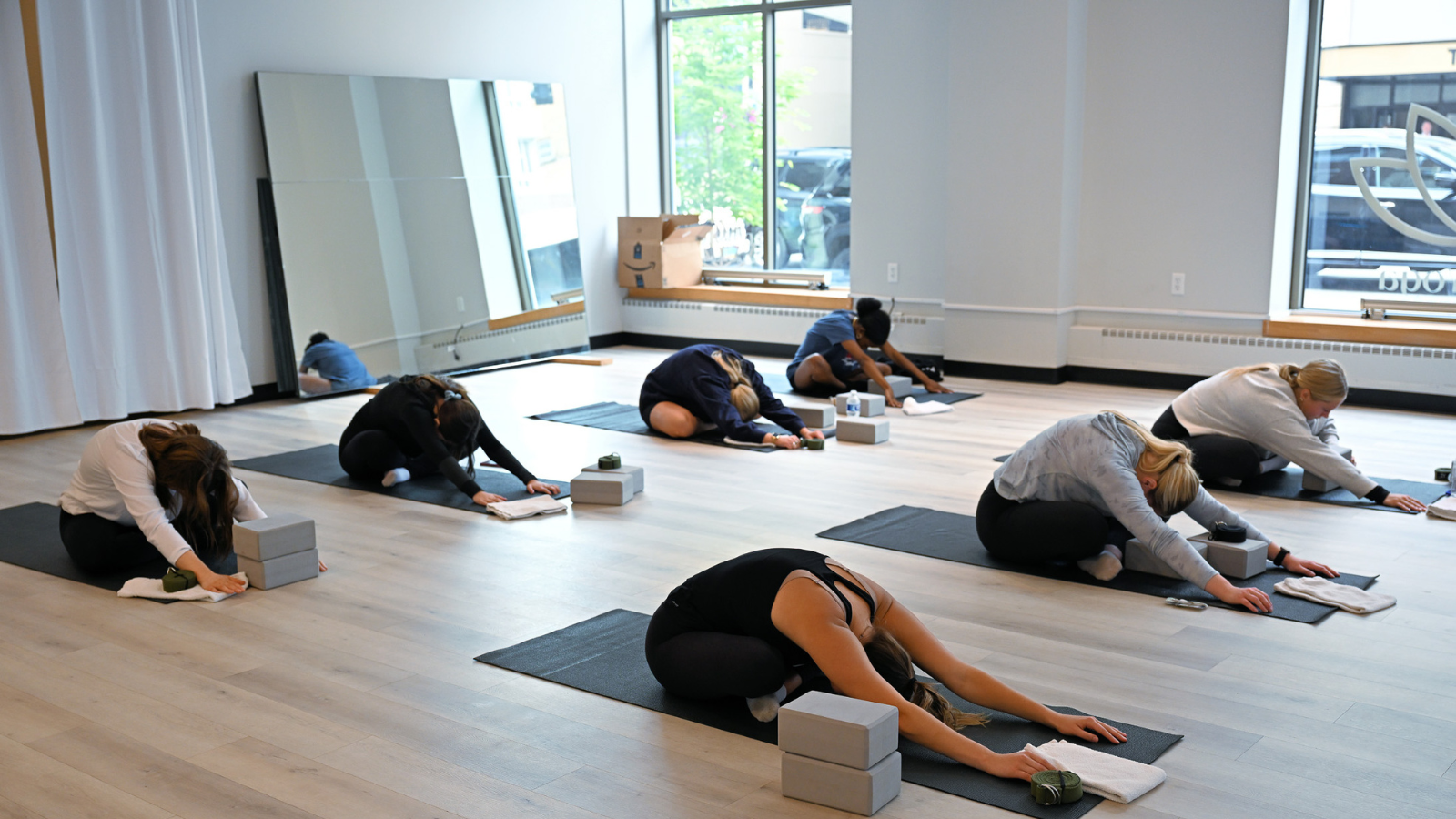 Lotus Yoga Group Class Photo Lotus yoga group exercise class leans over their mats together with the daylight pouring in