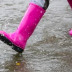 A pink rain boot stomps through the puddles on a rainy day in Grand Forks