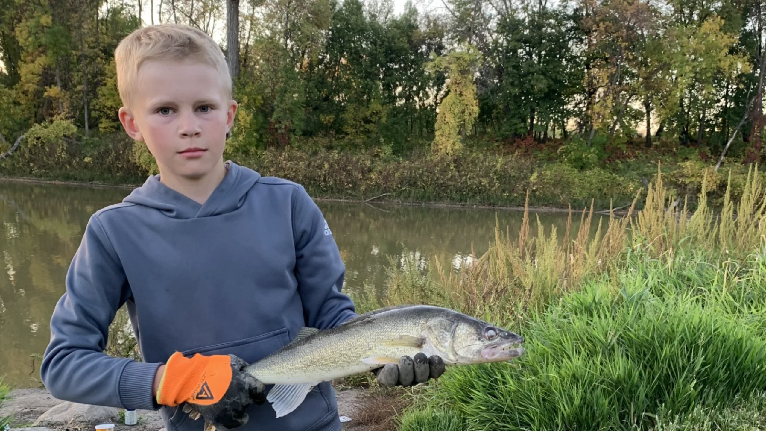 Hudson holds up a walleye after shore fishing from the Greenway in Grand Forks