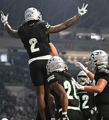 Men's football team celebrates a touchdown in their black uniforms